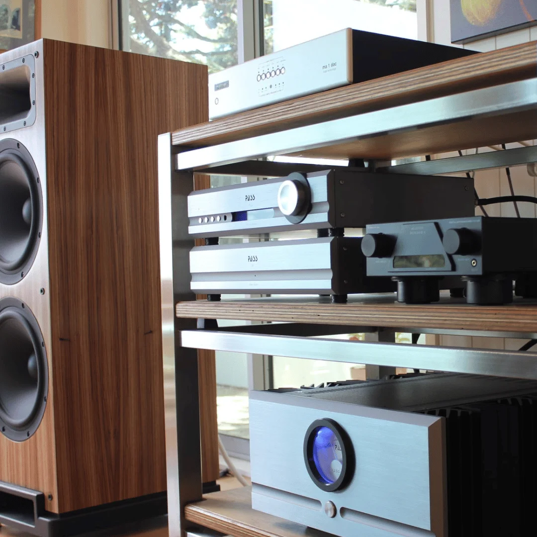 Luidspreker in walnoot op een Seismic Podium naast een hifi-rack